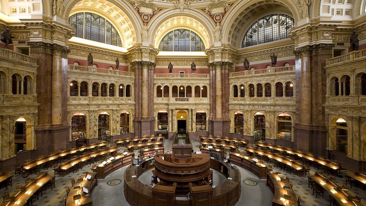 Readers working at long tables in a grand public library reading room
