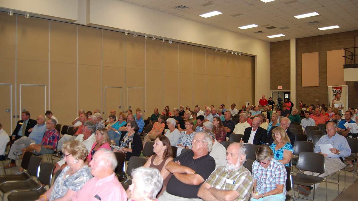 Audience members listening at a public hearing